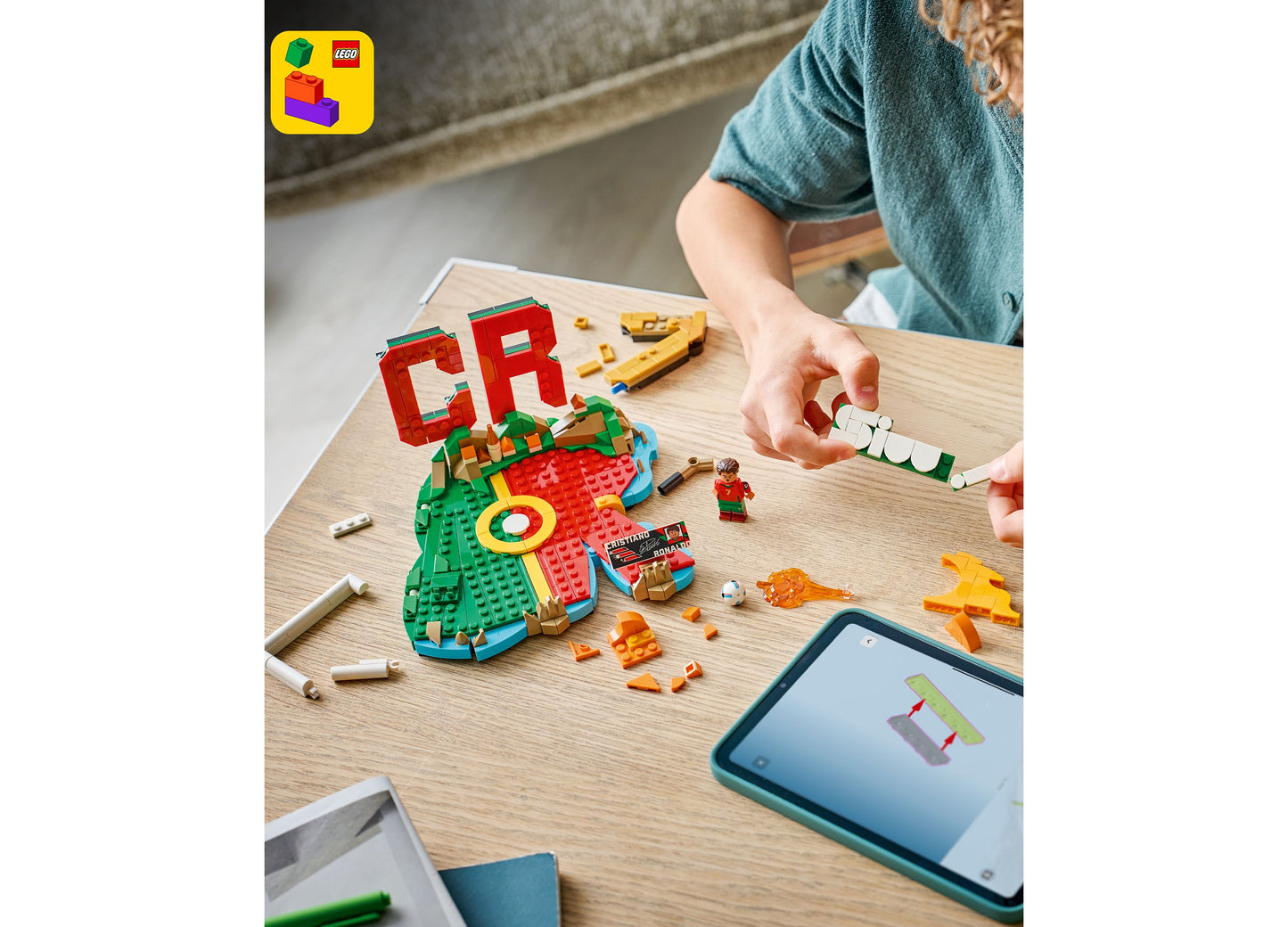 LEGO Cristiano Ronaldo Soccer Highlights 43012 set with red and green pieces being assembled on wooden table