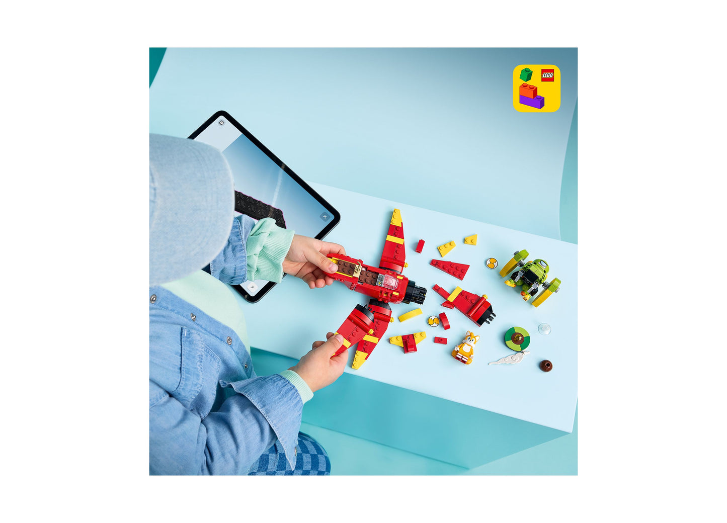LEGO Sonic Tails' Tornado-1 building set with red and yellow pieces, displayed with smartphone and minifigures