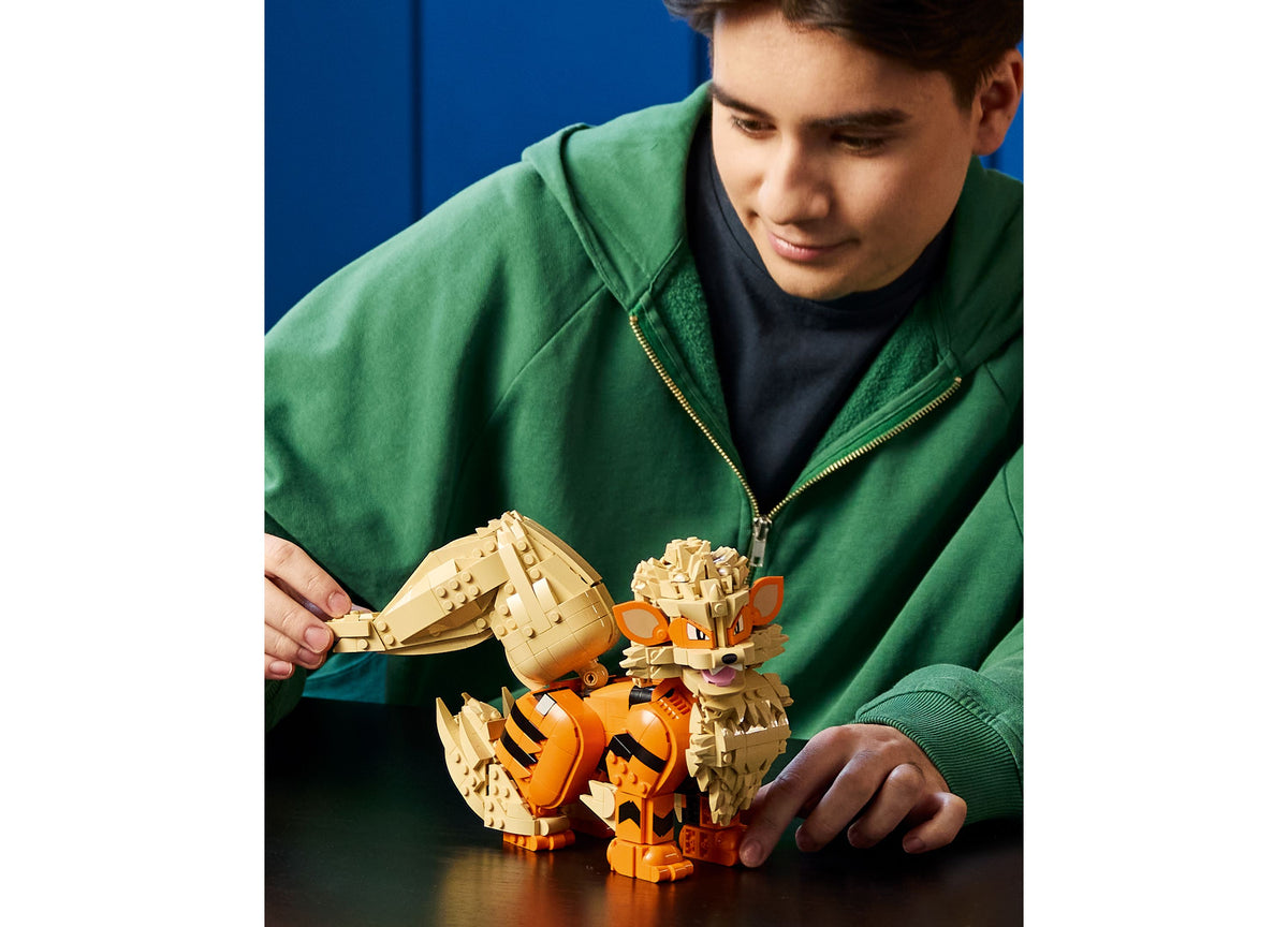 Building LEGO Pokémon Arcanine set with orange and tan pieces, for adult builders