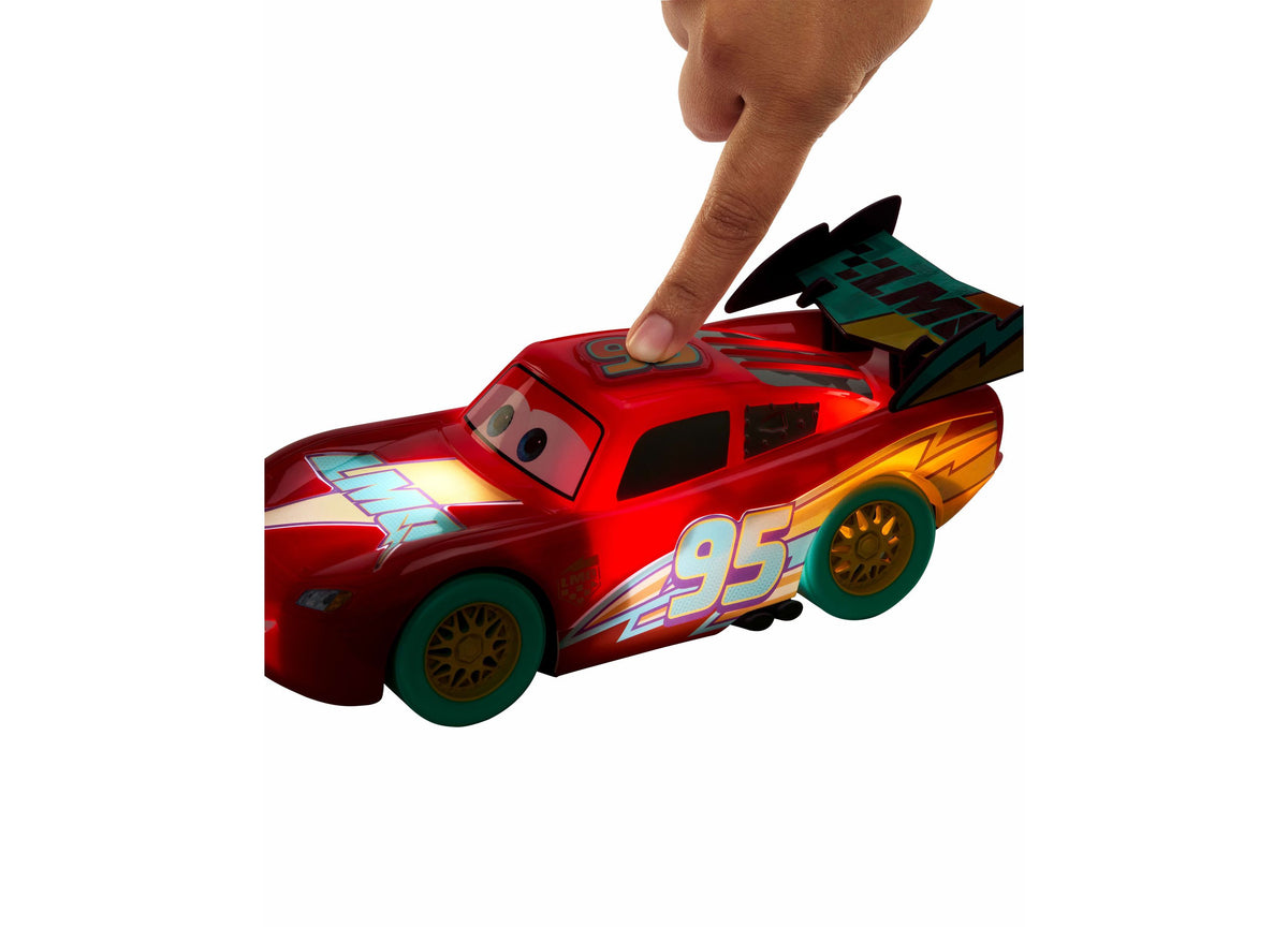 Red Lightning McQueen toy car with number 95, shown with hand pressing roof button to activate lights and sounds