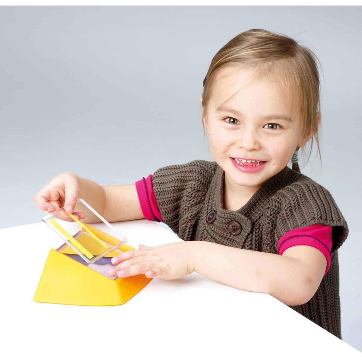 Young girl playing with SmartGames Color Code transparent tile logic puzzle game with yellow tiles