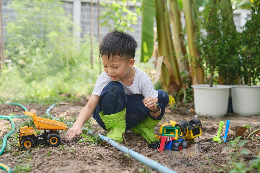 Boy playing outside with toy construction vehicles