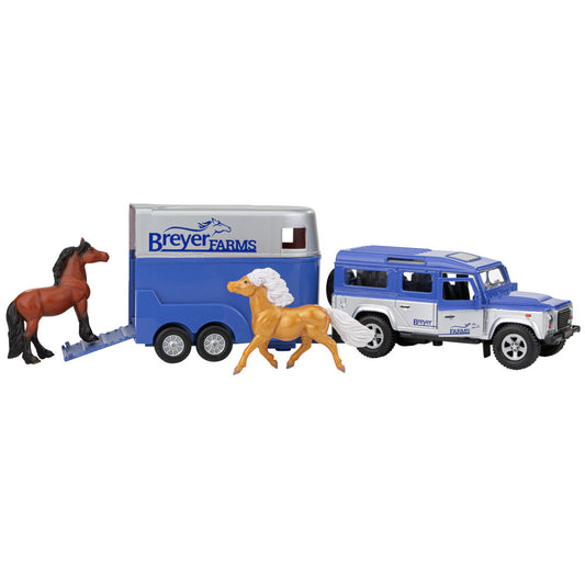 Breyer Farms playset with blue and white Land Rover, blue horse trailer, brown horse with black mane, and tan horse with white mane on plain background