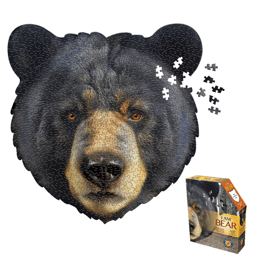 Bear-shaped jigsaw puzzle with black fur and tan face showing assembled puzzle with loose pieces scattered, displayed with product box