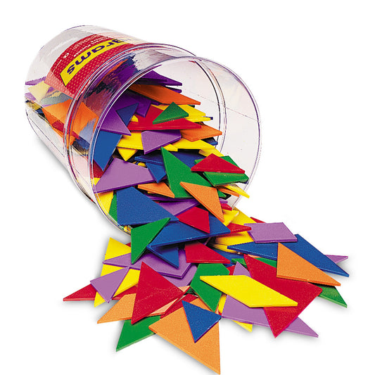 Clear plastic bucket tipped over with colorful foam tangram pieces spilling out, including red, blue, yellow, green, orange, and purple triangle and square shap