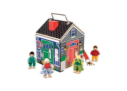 Wooden dollhouse with colorful doors and windows, handle on roof, four wooden dolls posed around it on plain background