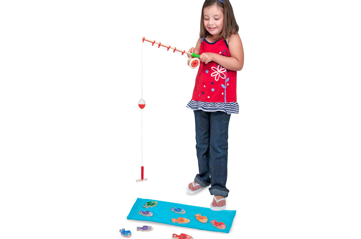 Melissa & Doug Catch & Count Wooden Magnetic Fishing Game with girl playing, red fishing rod, and numbered fish on bl...