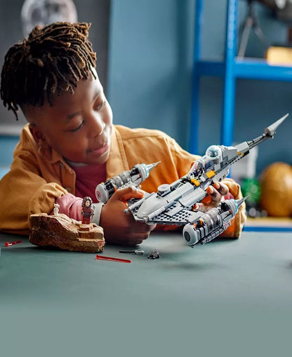 Child building LEGO Star Wars Mandalorian N-1 Starfighter set with white and gray spacecraft model