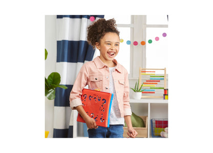 Child holding red Hasbro Guess Who Classic Character Guessing Game with blue accents in colorful playroom