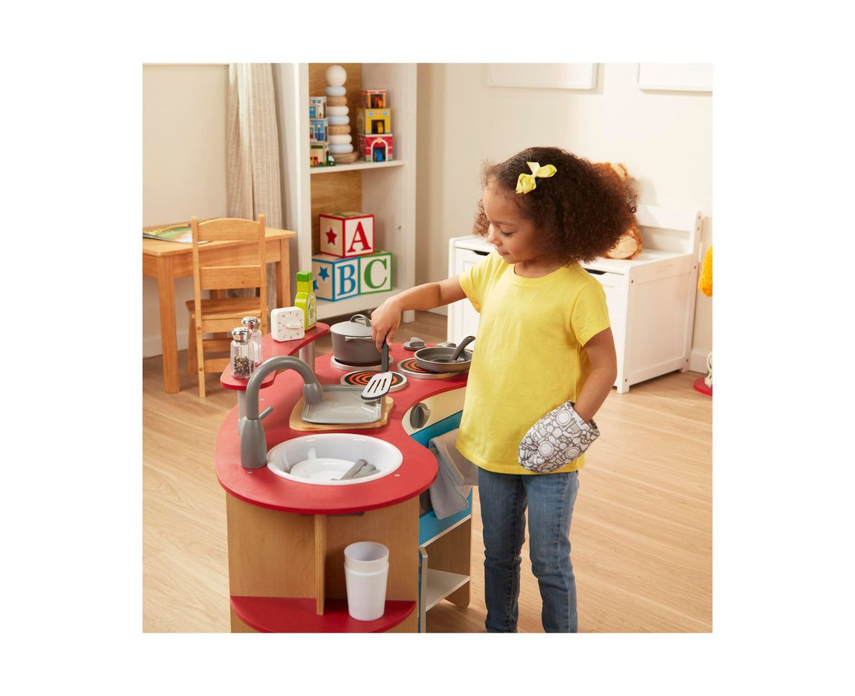 Melissa & Doug 22-Piece Play Kitchen Accessories Set with girl in yellow shirt playing at red play kitchen