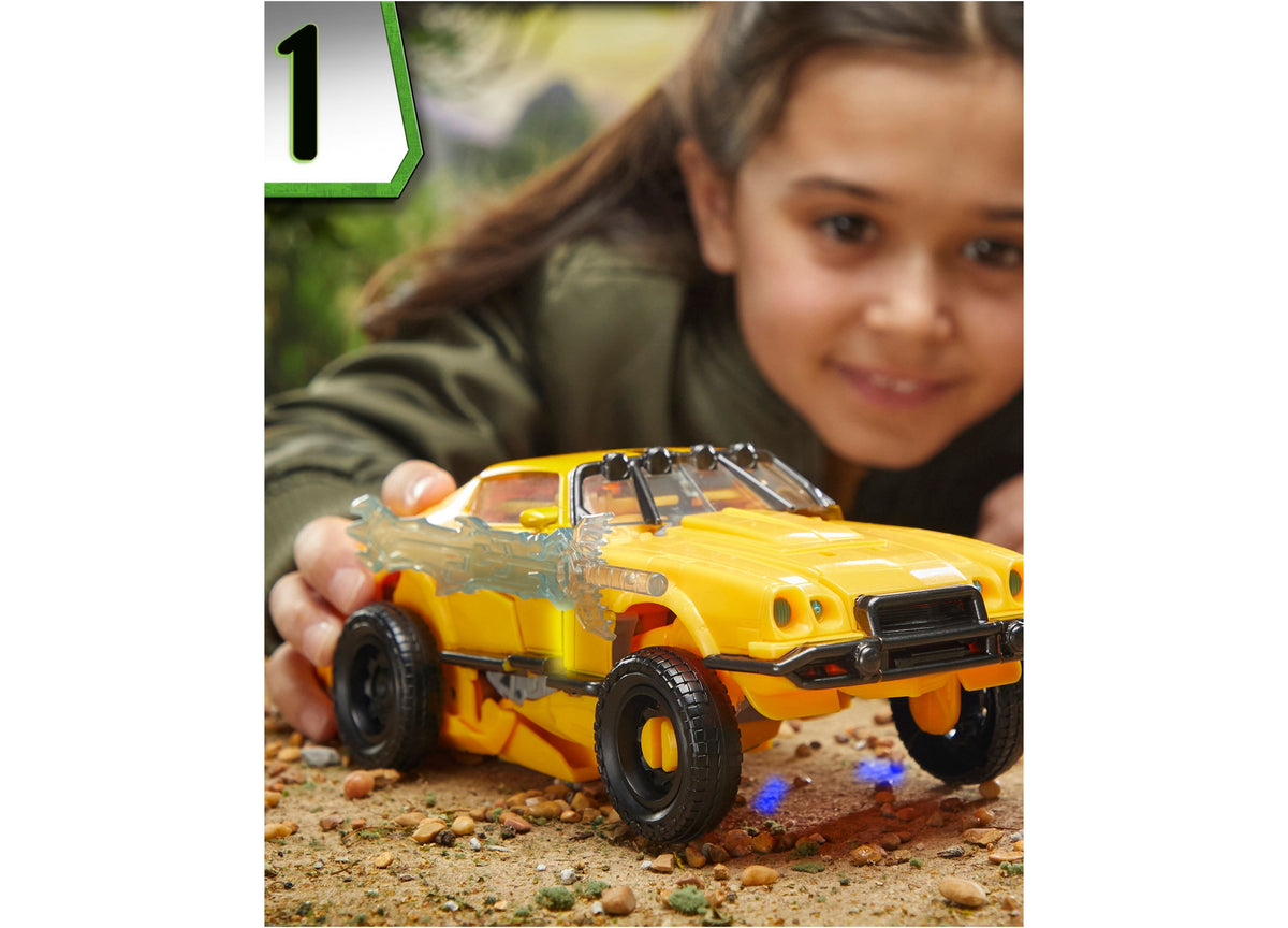 Child holding yellow Transformers Bumblebee 10-inch triple changer action figure in vehicle mode on sandy ground