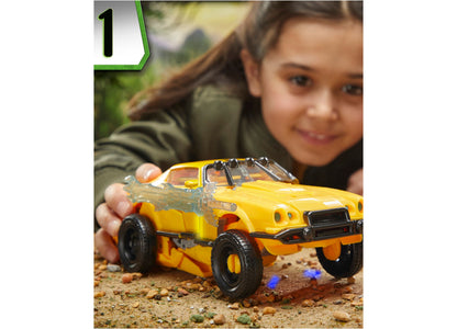 Child holding yellow Transformers Bumblebee 10-inch triple changer action figure in vehicle mode on sandy ground