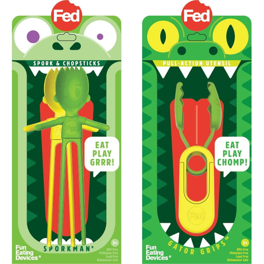 Two green character toy utensils in packaging: left shows Sporkman with purple eyes and yellow/red spork design labeled 'Eat Play Grrr'; right shows Gator Gripz