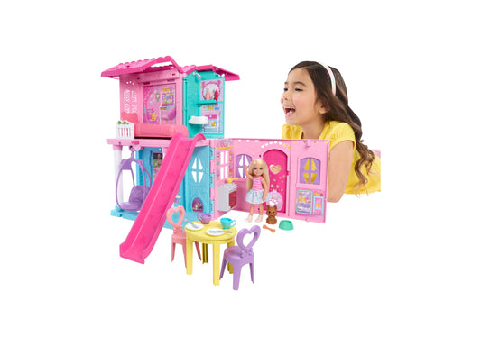 Barbie Chelsea Pop-Up Doll House with blonde doll, pink and turquoise playhouse featuring slide, furniture, and accessories, modeled by a child in yellow shirt