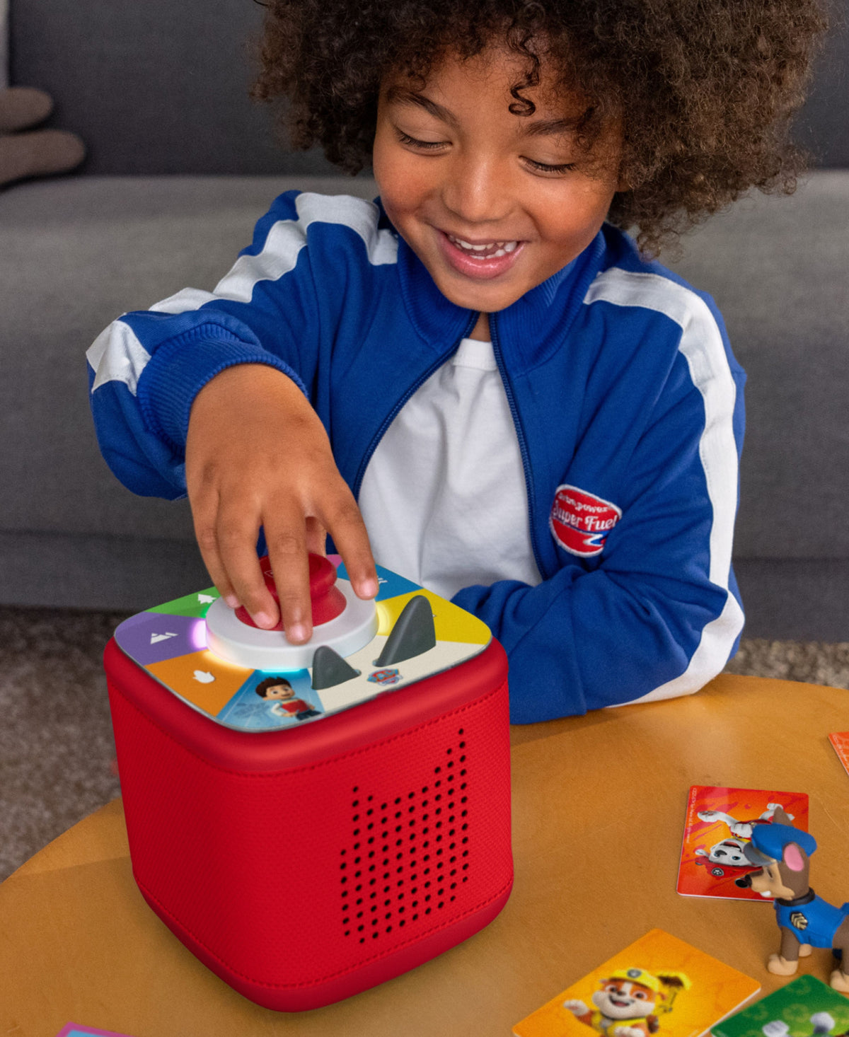 Child playing with red Tonies Tonieplay Controller featuring colorful buttons and character artwork
