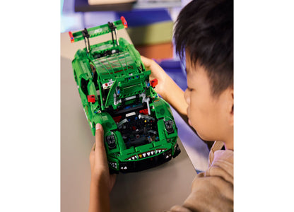 Child holding green LEGO Technic Porsche 911 GT3 R racing car with detailed engine visible
