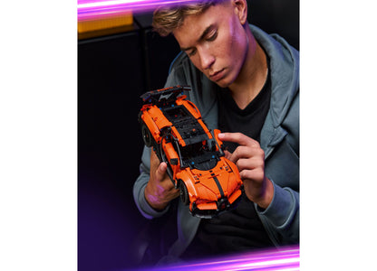 Teen holding orange and black LEGO Technic Bugatti Chiron Pur Sport hypercar building set 42222