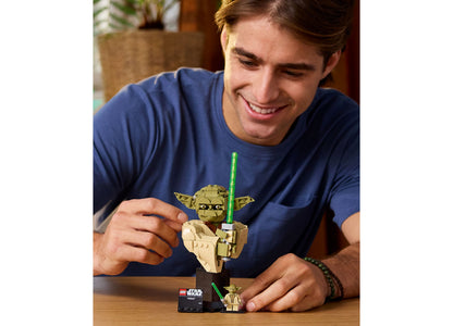 LEGO Star Wars Yoda Bust 75438 with green lightsaber and minifigure, displayed by person in blue shirt