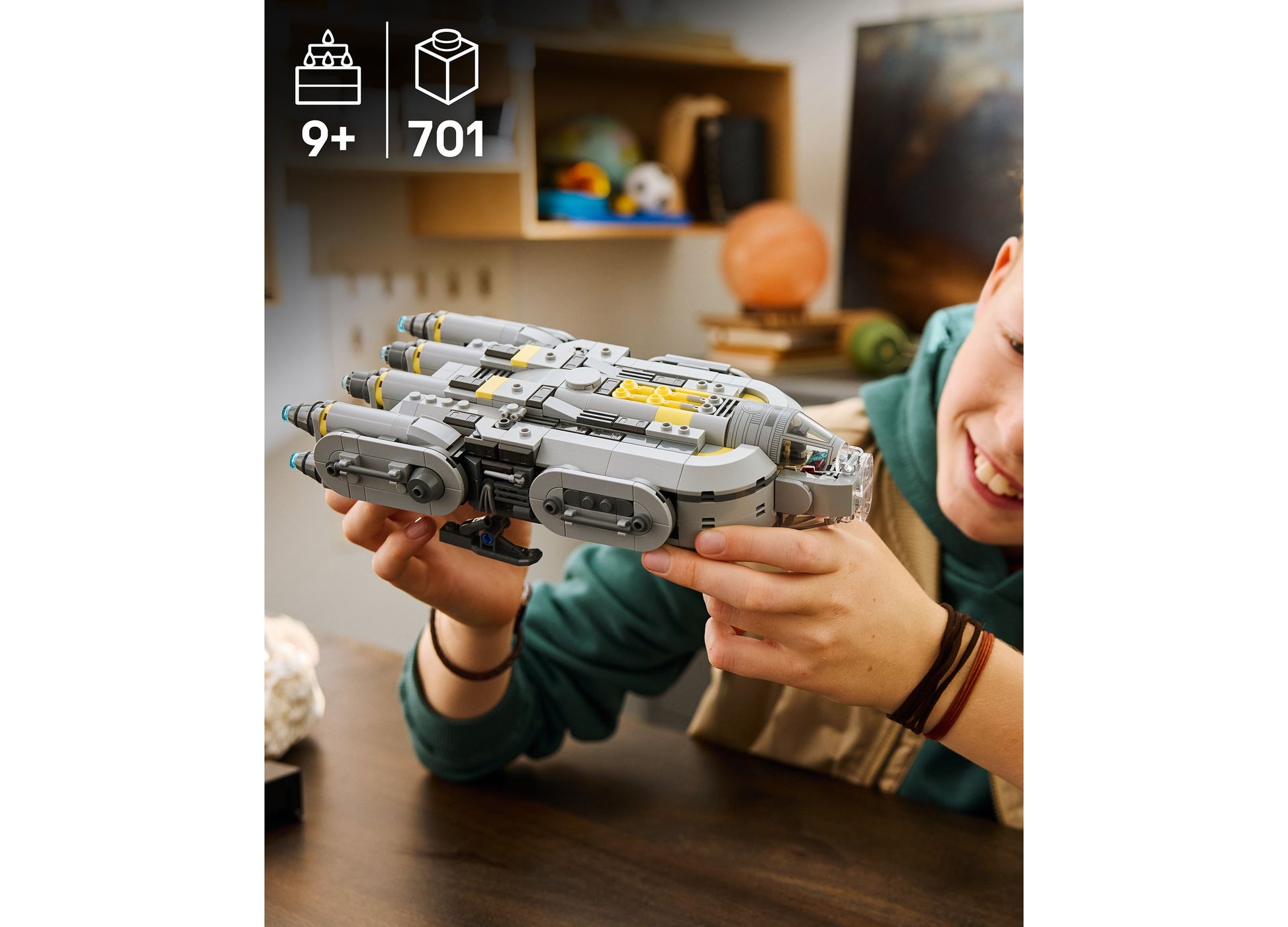 Child holding LEGO Star Wars Mandalorian Starship 75445 building set with gray and yellow pieces