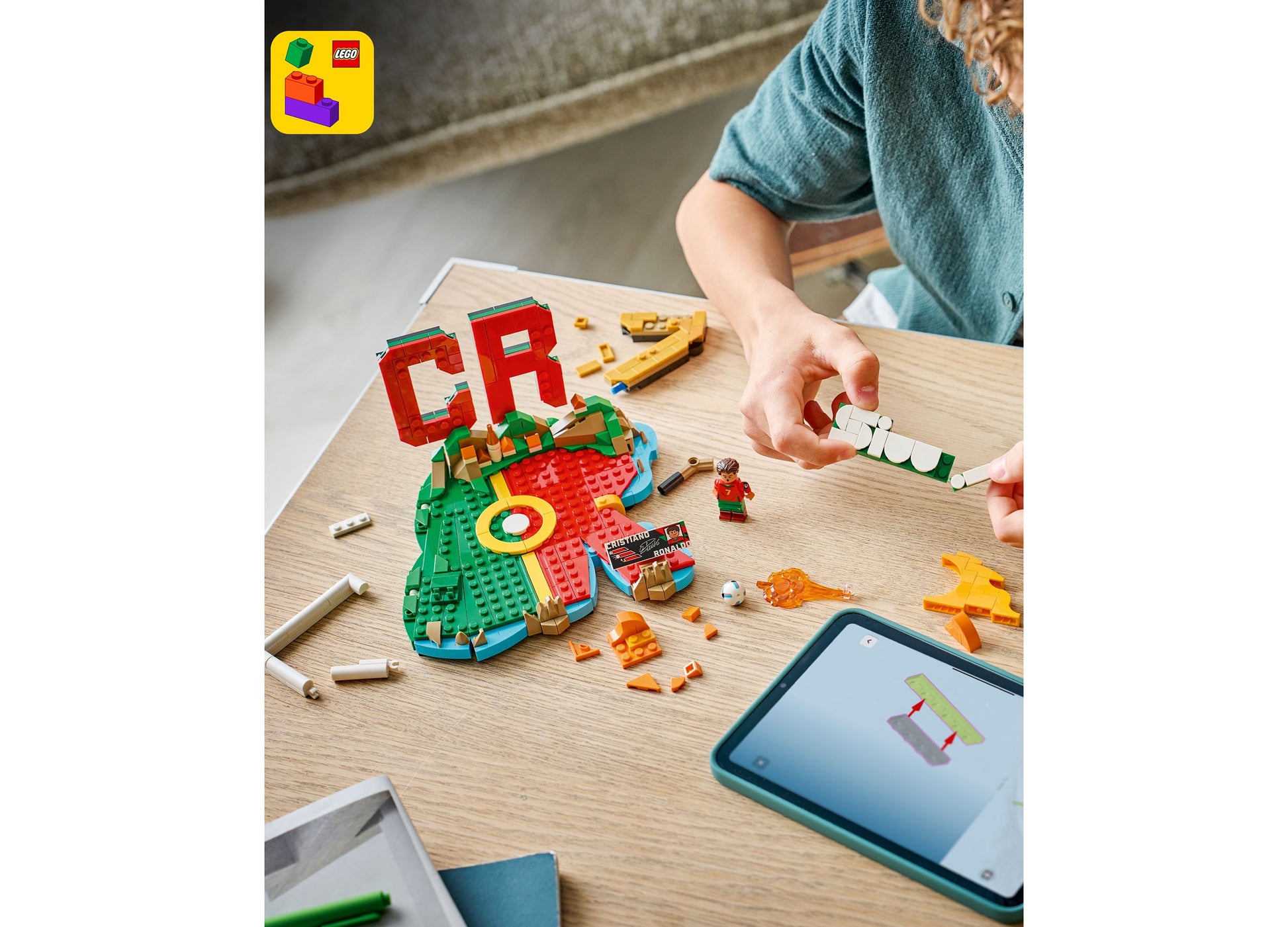 LEGO Cristiano Ronaldo Soccer Highlights 43012 set with red and green pieces being assembled on wooden table
