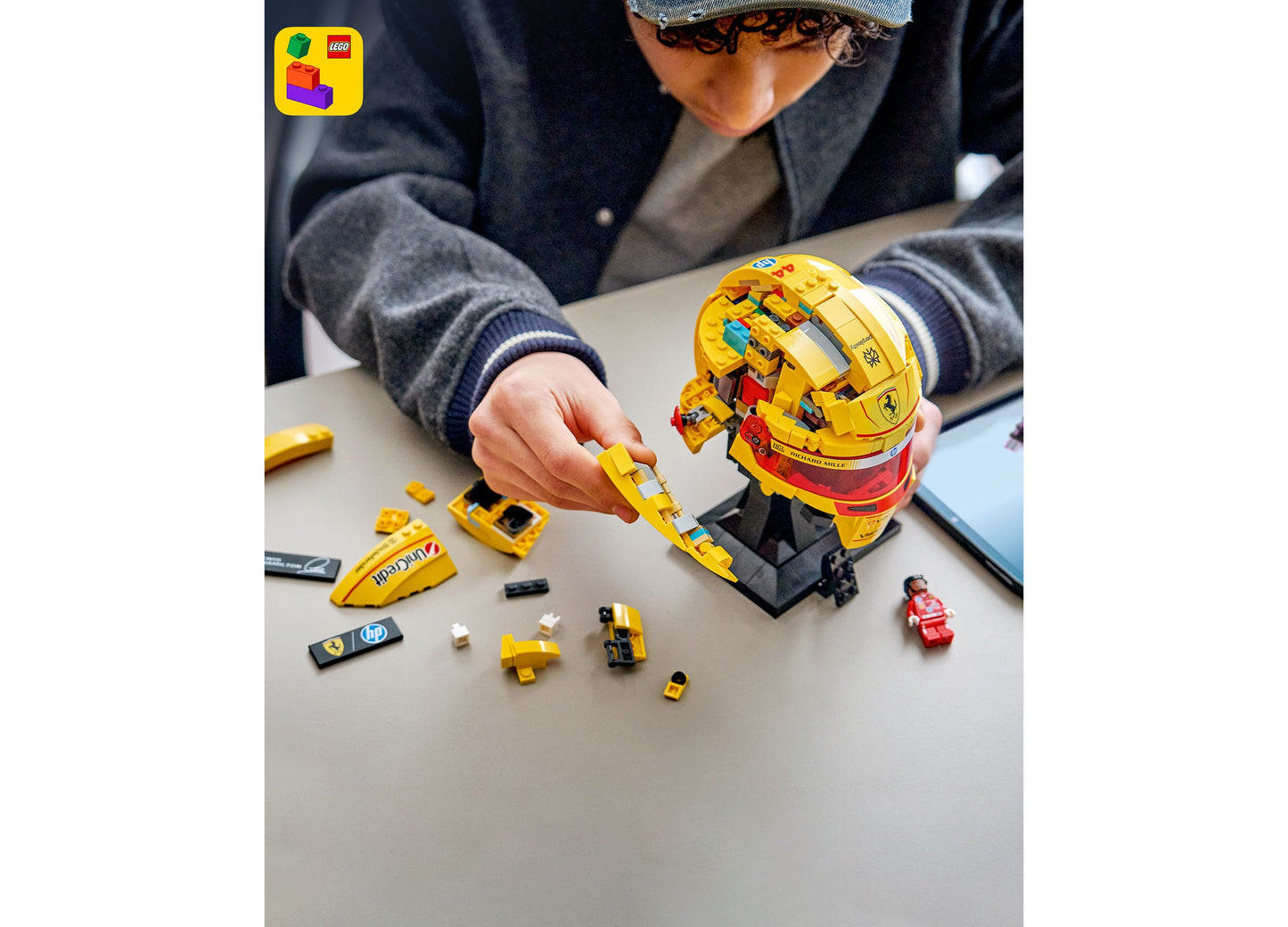 LEGO Scuderia Ferrari HP Lewis Hamilton Helmet 43022 being assembled by child, yellow and red pieces