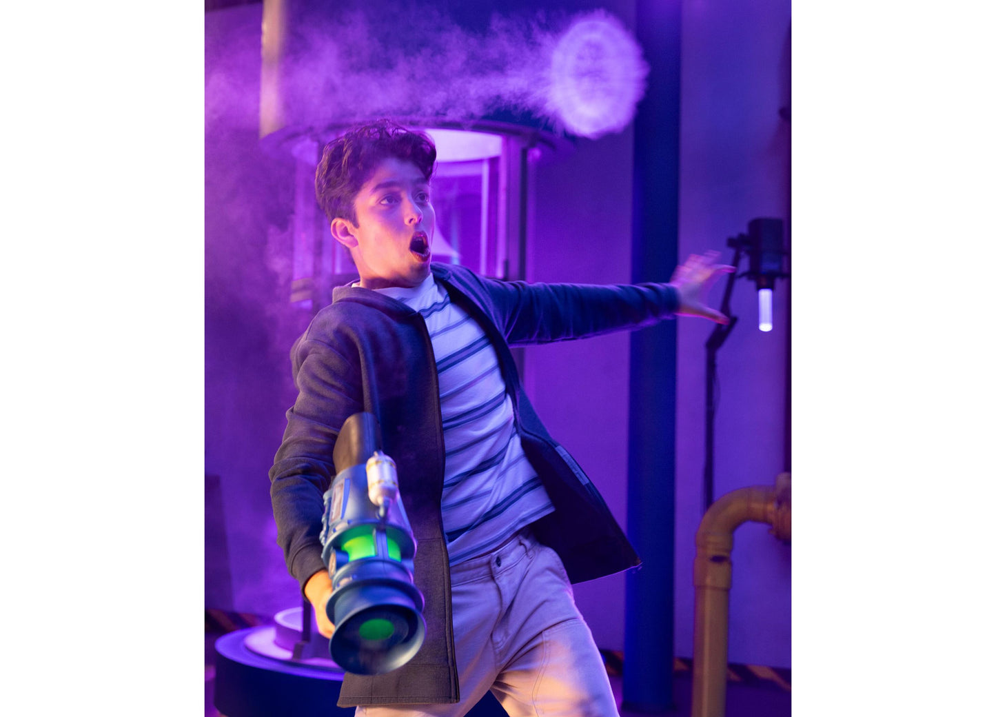 Boy holding green Despicable Me Minions 3 Supreme Fart Blaster toy in purple-lit room