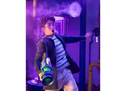 Boy holding green Despicable Me Minions 3 Supreme Fart Blaster toy in purple-lit room