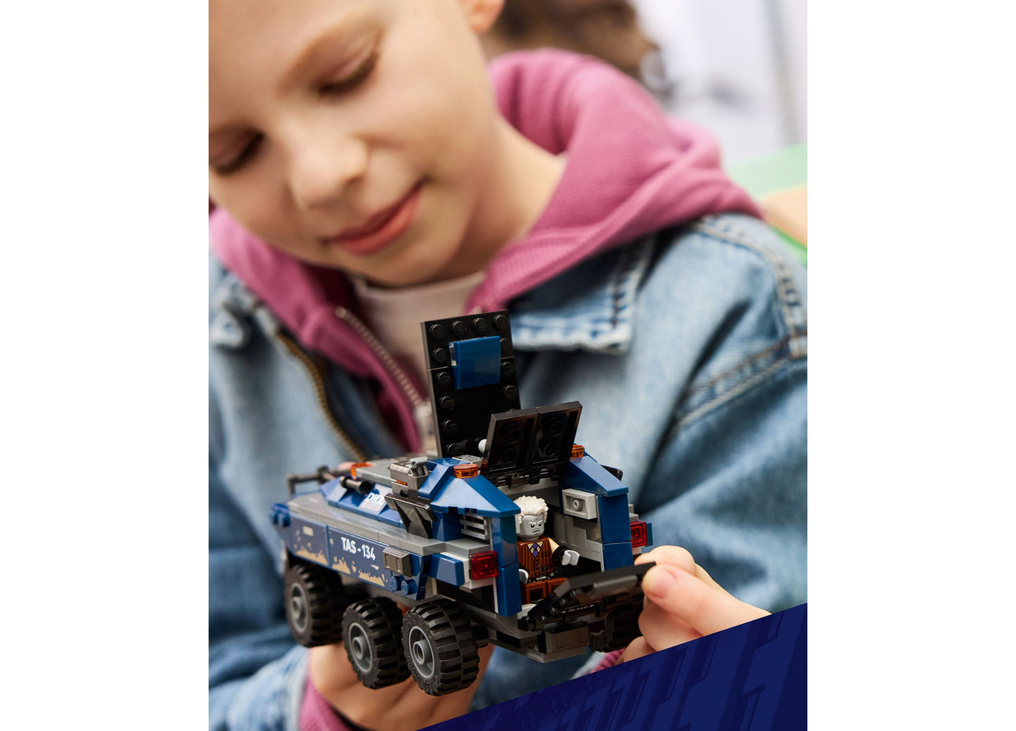 Child holding LEGO Marvel Spider-Man Prison Transport Chase set 76349 with blue and black buildable vehicle