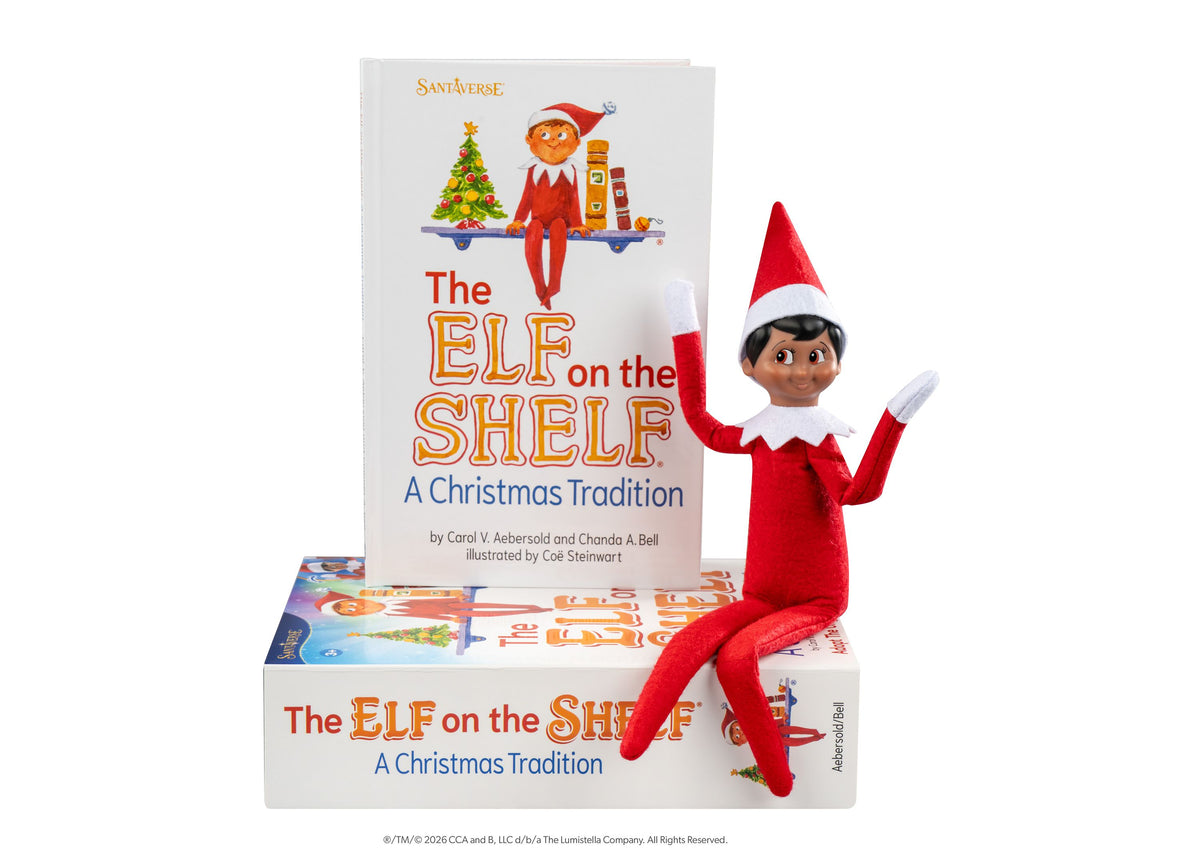 Elf on the Shelf Scout Elf Boy figure with brown eyes in red suit and hat, posed next to storybook and boxed set