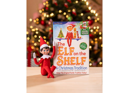 Elf on the Shelf Scout Elf Boy figure in red outfit with storybook and accessories against decorated Christmas tree b...