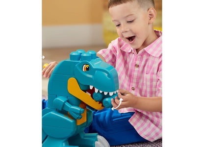 Turquoise Mega Bloks Build & Chomp Dinosaur set with yellow jaw, child in pink shirt playing with chomping T-Rex toy