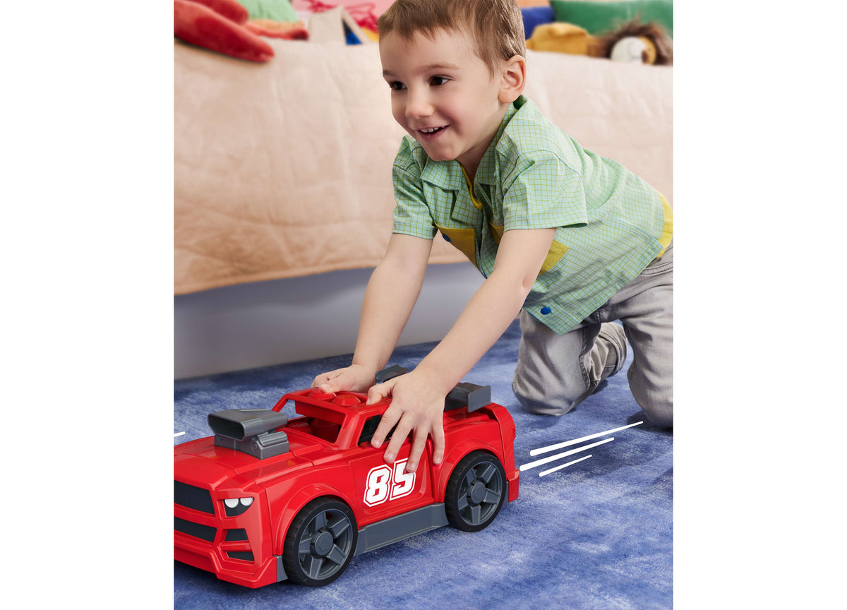 Red race car toy with number 85, rolling wheels, held by child playing on blue mat