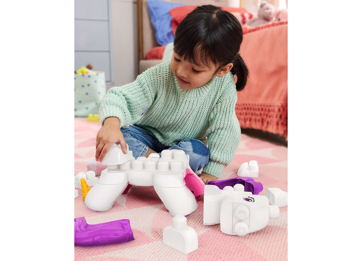 Child playing with white and purple Mega Bloks Build & Enchant Unicorn 26-Piece Building Set on pink mat