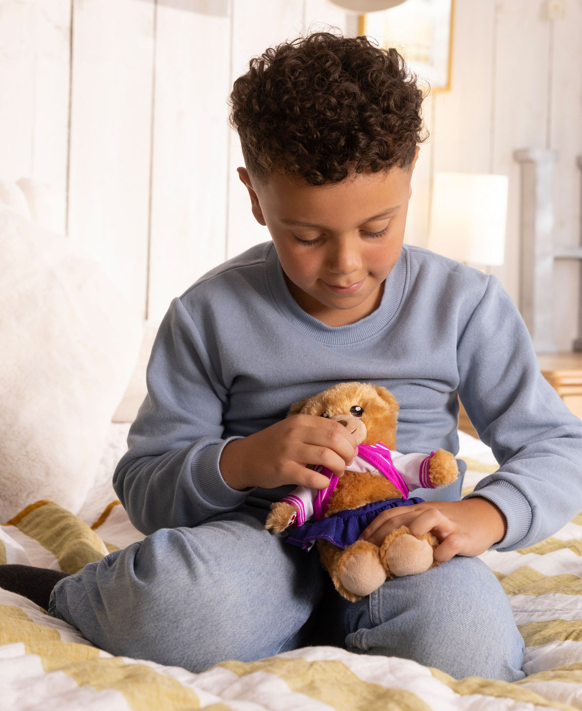 Child dressing brown bear in purple and pink outfit from Casdon Furtastic Friend pack