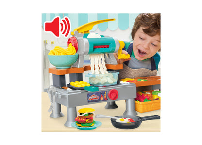 Play-Doh Super Sizzlin Kitchen Playset with child playing, featuring turquoise and gray kitchen station with pasta ma...
