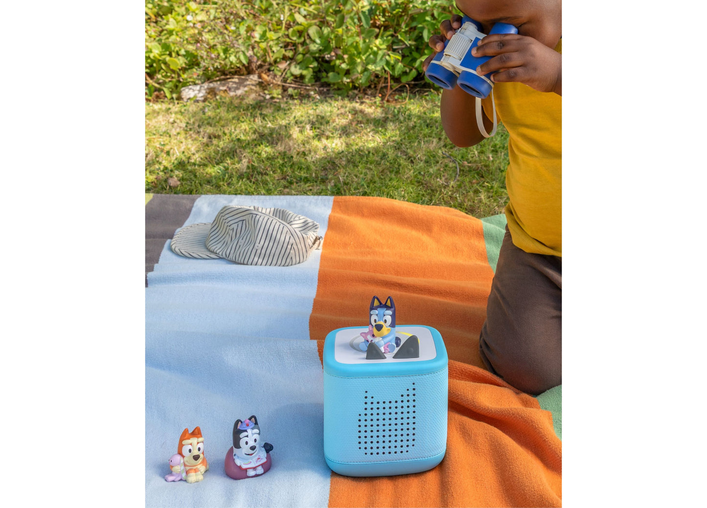 Tonies Bluey Tonie blue speaker with Bluey figurines on colorful blanket outdoors