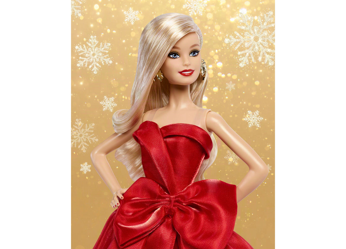 Holiday Barbie doll in red strapless gown with bow detail, blonde hair, red lips, and gold earrings against gold snow...