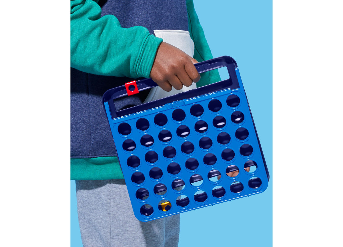 Child holding blue Hasbro Gaming Connect 4 board game with red checker piece, 42-piece set for ages 6+