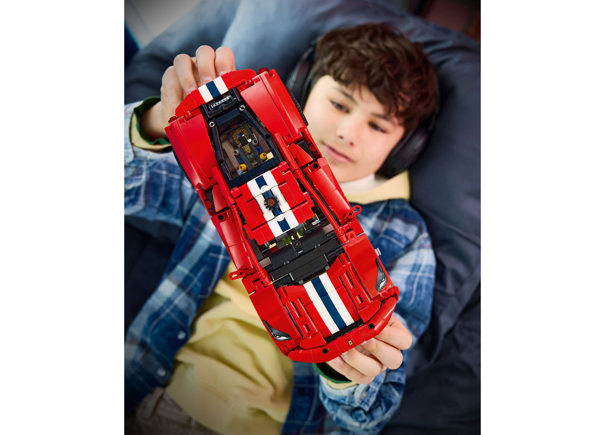 Child holding red LEGO Technic Ferrari 488 PISTA building set with white racing stripes