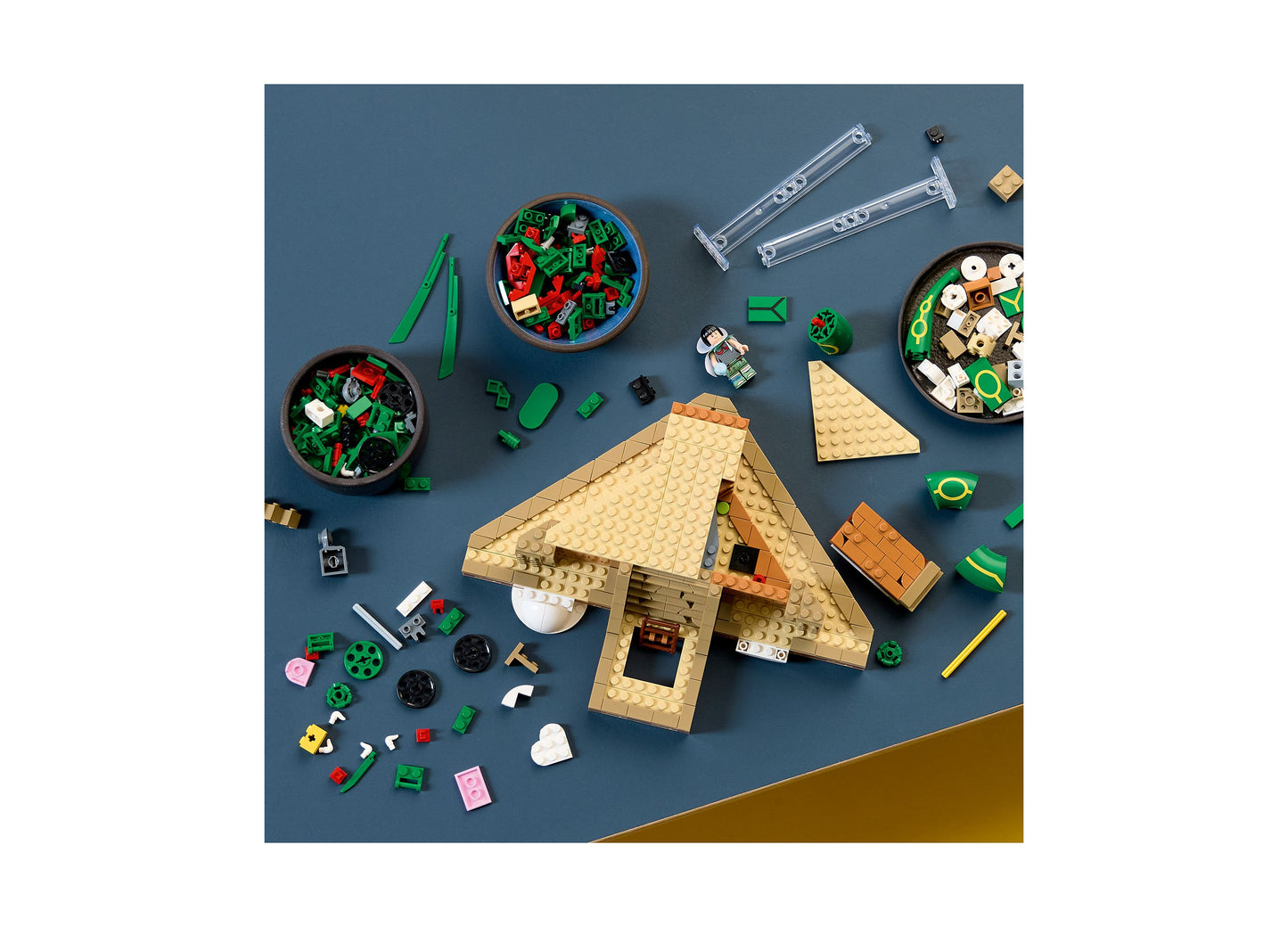 LEGO Pokémon Rayquaza building set with tan and green pieces, minifigures, and accessories displayed on blue background