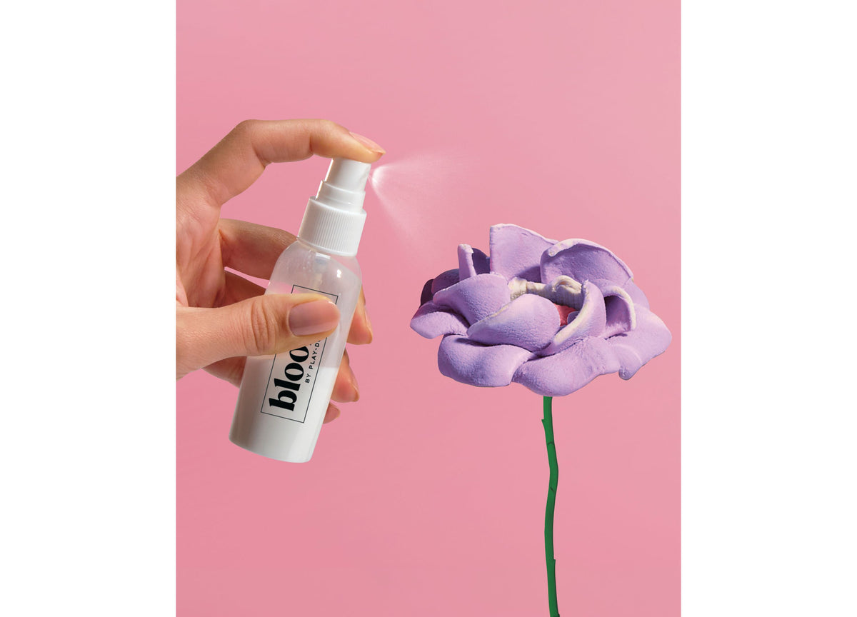 Play-Doh Blooms DIY Garden Bouquet Kit with purple flower and spray bottle on pink background