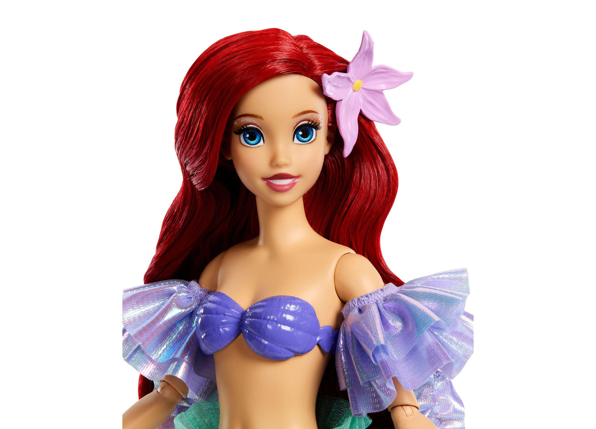 Disney Princess Ariel doll with long red hair, pink flower clip, blue shell top with purple iridescent sleeves, and g...