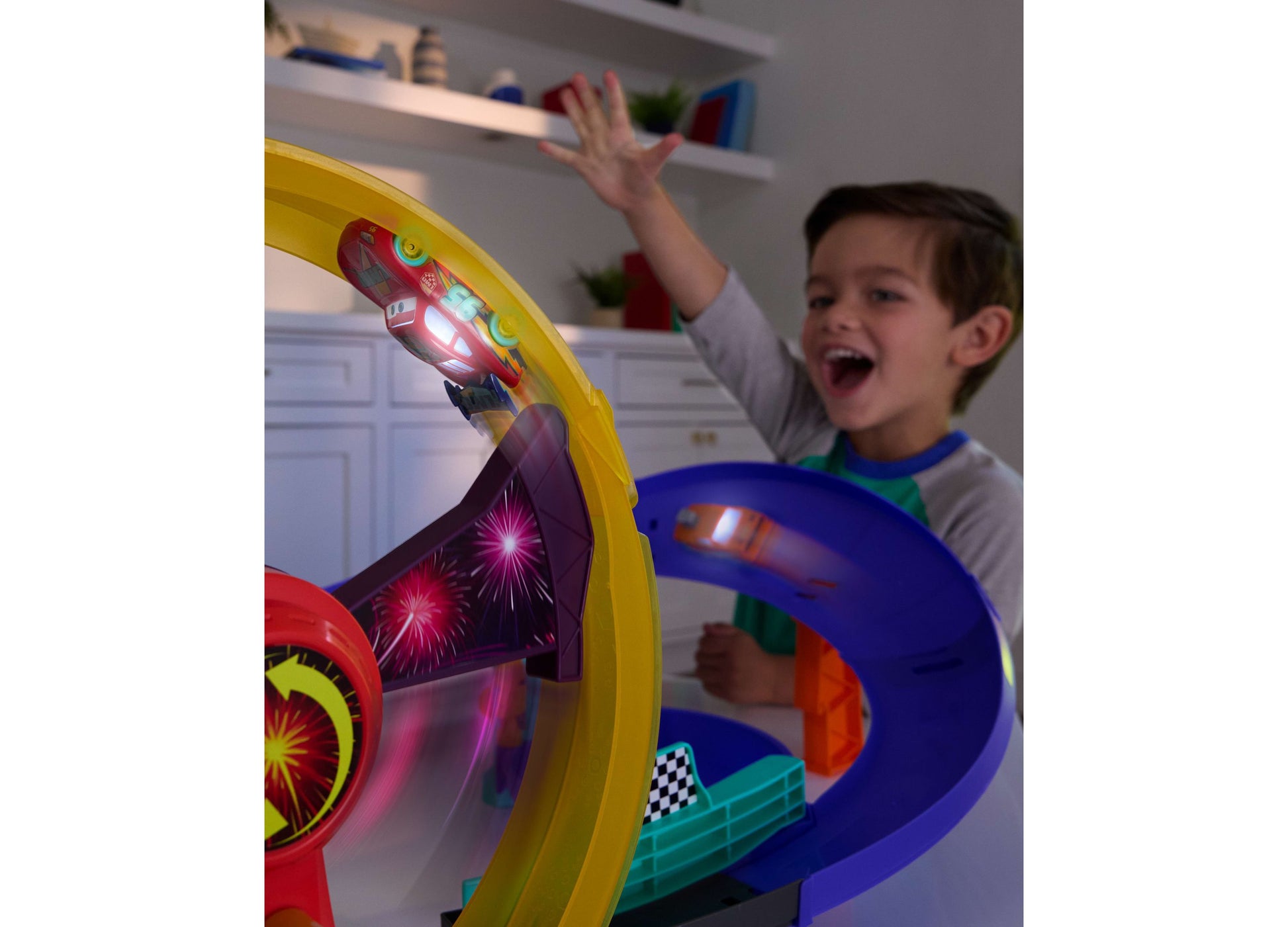 Cars Lightning McQueen Light-Up Celebration Raceway playset with yellow track and blue base, child playing