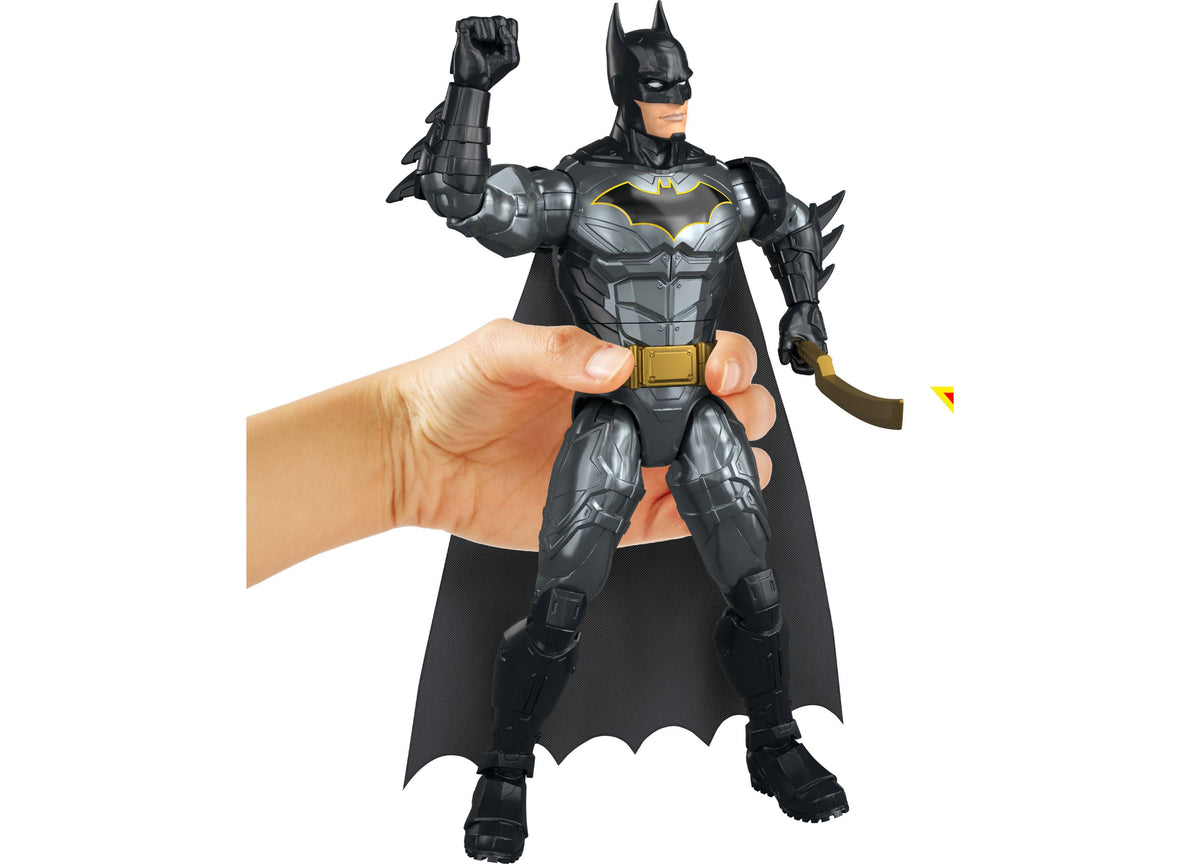 DC Comics Batman 12" Action Figure held in hand, featuring black armor with yellow bat logo and gold belt