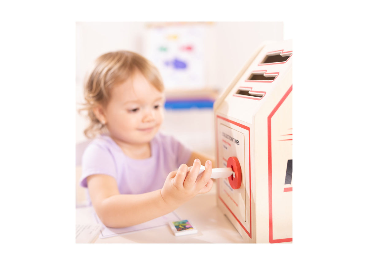 Child in purple shirt using Melissa & Doug Stamp & Sort Mailbox Playset with red and cream mailbox