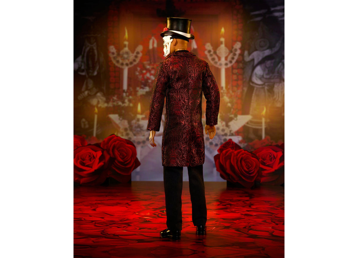 Barbie Día De Muertos Ken doll wearing crimson jacket with skeleton embroidery, mask, and top hat, standing before re...