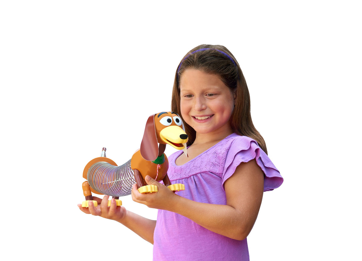 Toy Story Slinky Dog Pull Toy in orange and yellow with floppy ears, held by smiling child in purple shirt