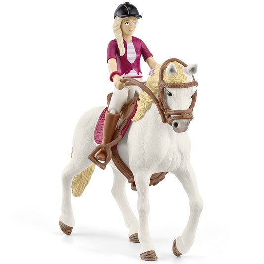 Doll figure with blonde braided hair wearing burgundy shirt and black riding helmet, mounted on white horse with brown saddle and reins