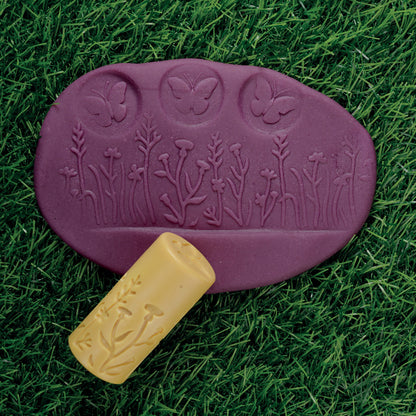 Let's Roll Garden Bugs Clay Stamper Set with purple oval mold and yellow roller tool on grass