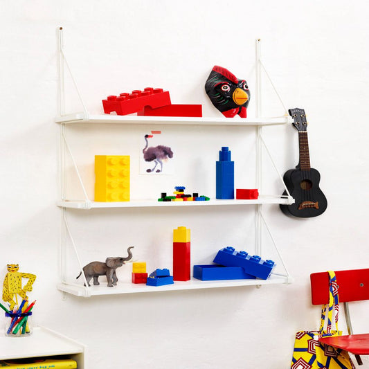 White wall-mounted shelving unit displaying various toys including red and blue LEGO bricks, a black Angry Birds plush, a purple ostrich figure, a black acousti
